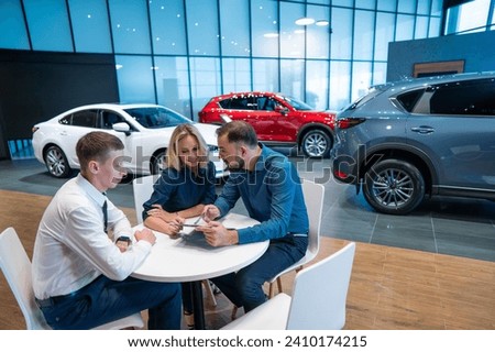 Happy caucasian couple signs a contract for the purchase of a car salon.