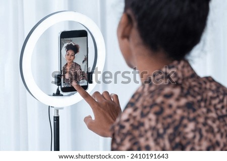 Woman influencer shoot live streaming vlog video review clothes crucial social media or blog. Happy young girl with apparel studio lighting for marketing recording session broadcasting online. Royalty-Free Stock Photo #2410191643