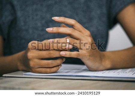 Woman pulling a wedding ring from finger. Divorce and ending of relationship concept.  Royalty-Free Stock Photo #2410195129
