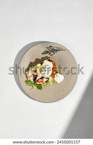 Top view of a zucchini waffle topped with crab and a poached egg, served on a plate with a modern aesthetic.