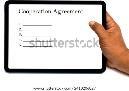 hand holding a computer tablet with a screen displaying the words of a cooperation agreement.  taxation concept