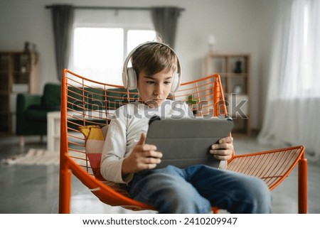 One schoolboy caucasian boy sit at home use digital tablet