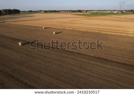 aerial view of hay ball of wheat straw in large field at early sunset in summer time in northern Italy