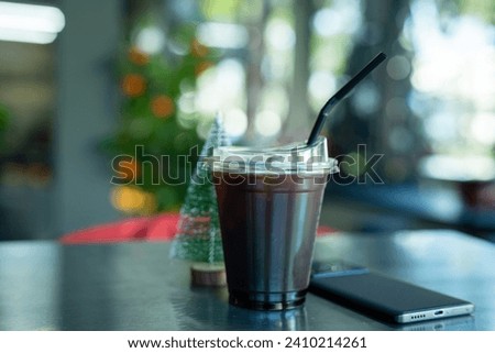 Americano iced coffee or black coffee in cup with smartphone and small Christmas tree on wood desk on top view In a coffee shop at the cafe,during business work