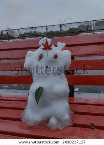 Cute snowman sitting on the red bench