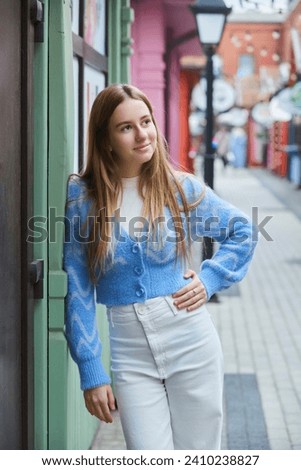 A student girl stands in beautiful clothes in the middle of a city street. Photo shoot for a girl.