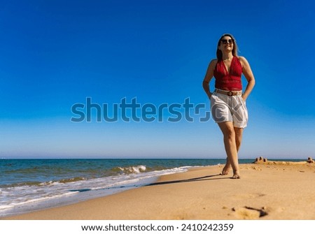 Beautiful mid adult woman walking on sunny beach 
