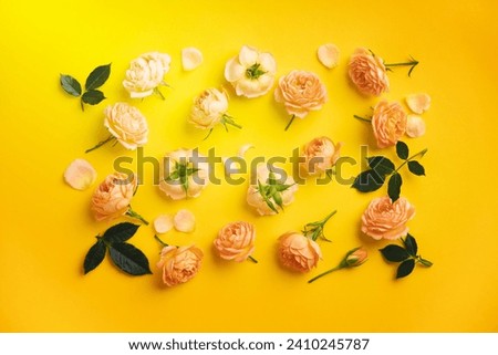 Floral pattern with pink roses and leaves on yellow background, flat lay