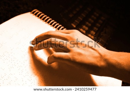 Hand and braille's book, reading and studying braille, colored background for text, orange photo