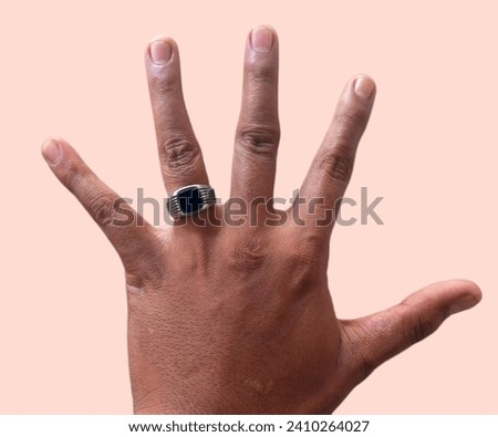 A man's hand and a ring on a finger against a cheap red background