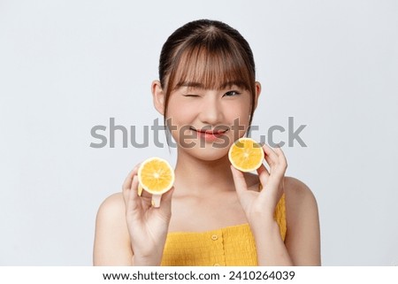 Organic cosmetics concept. A young girl with clean skin holds lemon slice near her face