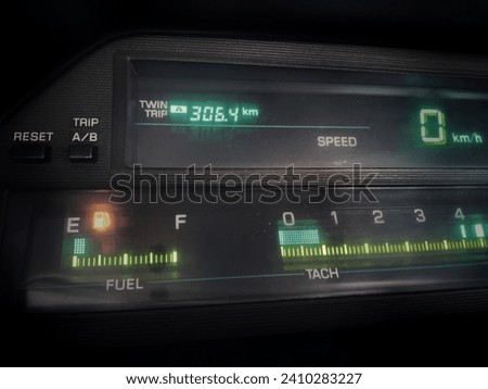 The image looks a bit blurry and old from the digital car cluster meter which has low fuel levels and turns on the low fuel indicator. Royalty-Free Stock Photo #2410283227