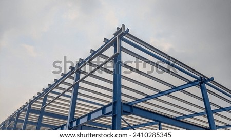 Steel frame structure, steel frame workshop is under construction against a blue sky, blue steel in steel installation construction Royalty-Free Stock Photo #2410285345