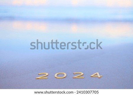 handwritten inscription 2024 on the sand by the sea, happy new year 