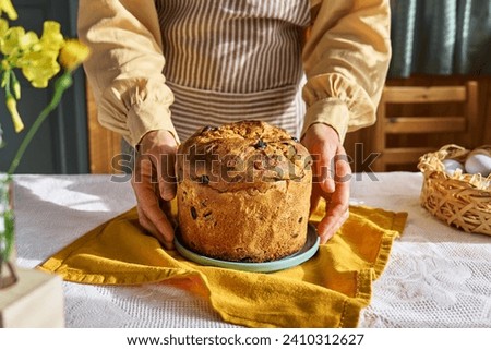 Female hands putting Easter cake on the table. Traditional easter cake or sweet bread with topping. Easter treat. Royalty-Free Stock Photo #2410312627
