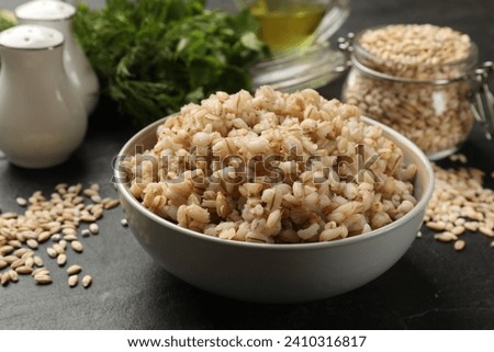 Tasty pearl barley porridge in bowl on dark table, closeup Royalty-Free Stock Photo #2410316817