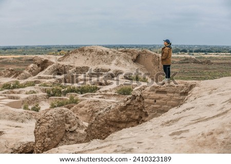 A asia young girl standing on the ruins of Toprak Kala, one of the Desert Castles of Ancient Khorezm traditionally known as Elliq Qala, Unesco World Heritage Site in Karakpakstan, Kyzylkum desert