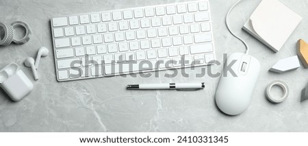 Flat lay composition with wired computer mouse and keyboard on light grey marble table. Space for text