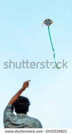 A picture of a guy flying a kite the blurred head in the foreground. Focus on the kite that is flying in the sky