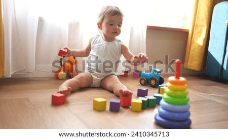 baby plays with toys cubes. kindergarten a teaching children kid dream concept. baby on floor of the house plays with a pyramid lifestyle and cubes toys development of fine motor skills Royalty-Free Stock Photo #2410345713