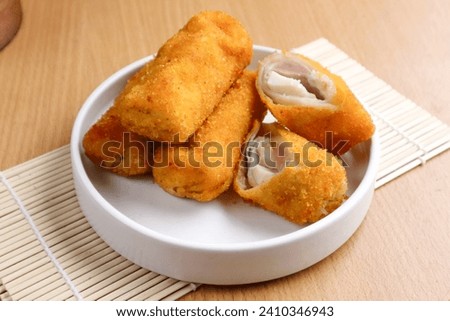 kue risoles mayo (risoles mayo cake) on wooden tray and penaut sauce served on table top. risoles mayo cake is one of popular indonesian foods. Royalty-Free Stock Photo #2410346943