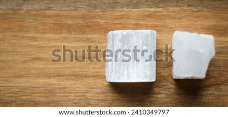 Piece of natural selenite on the wooden background.  Royalty-Free Stock Photo #2410349797