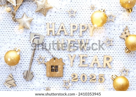 House key with keychain cottage on festive background with stars, lights of garlands. New Year 2025 wooden letters, greeting card. Purchase, construction, relocation, mortgage, insurance