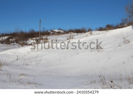 A snowy field with trees and a house in the distance