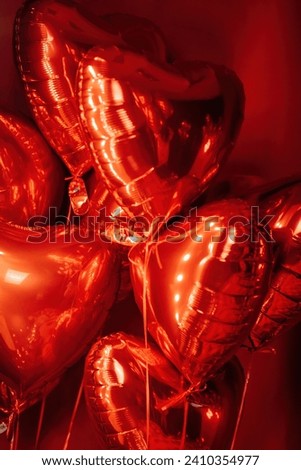 Extravagant glamour background with red foil heart air balloons for love party. Beautiful romantic burlesque room place for st valentines holiday illuminated vanity makeup mirror muffled light Royalty-Free Stock Photo #2410354977
