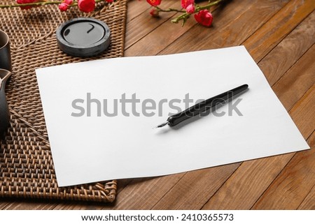 Blank sheet of paper, ink and nib pen on wooden table. International Haiku Poetry Day Royalty-Free Stock Photo #2410365573