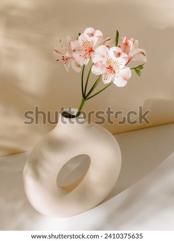 Vase with flower bouquet on the table with aesthetic sunlight shadows. Ceramic vase with pink flowers, bohemian home poster, interior decoration