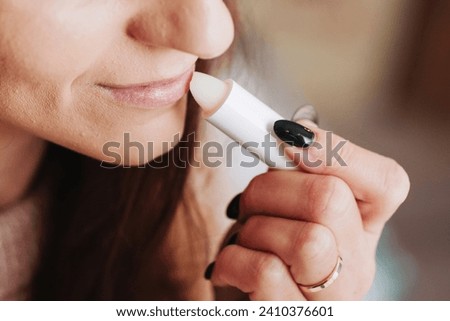 Woman using petrolatum on her mouth. Closeup lips background. Applying lip salve on lips with lipstick. Beauty background. Young girl skin care. Cosmetics for moisturize. Happy woman smile. Royalty-Free Stock Photo #2410376601