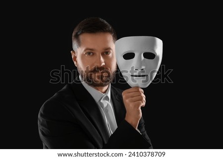 Multiple personality concept. Man with mask on black background