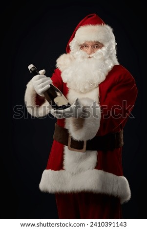Modern Santa Claus celebrates Christmas with champagne. Corporate party. New Year and Christmas for adults. Black studio background. Royalty-Free Stock Photo #2410391143