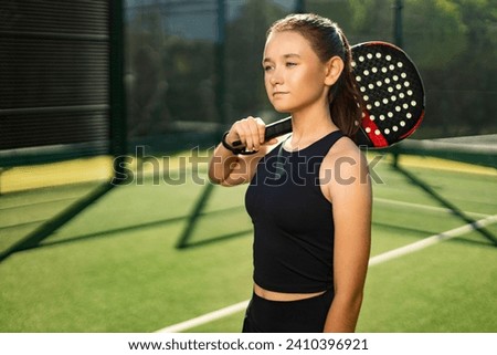 Padel tennis player with racket and ball in hands. Girl athlete with paddle racket on court outdoors. Sport concept. Download a high quality photo for the design of a sports app or web site.