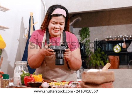 Cute Asian fat girl is happy cooking in the kitchen at home. She held a camera and took pictures of her finished food. Fast food. Pizza