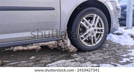 Dirty ice and snow build up in the wheel arch of a car in a freezing cold winter Royalty-Free Stock Photo #2410427341