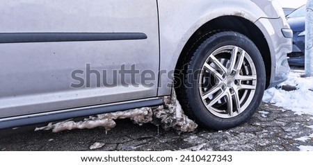 Dirty ice and snow build up in the wheel arch of a car in a freezing cold winter Royalty-Free Stock Photo #2410427343