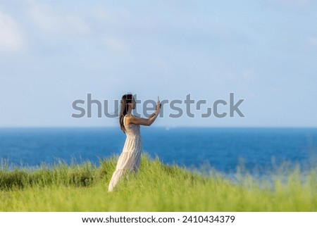 Woman use of mobile phone to take photo beside the sea