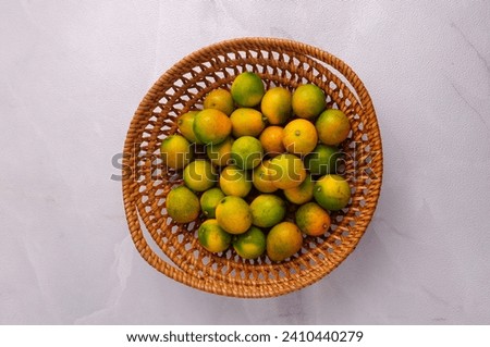 Triphasia trifolia also called limeberry, lime berry, "sweet lime" or limoncitong kastila is a species of Triphasia in the family Rutac.  Sweet Lime in the basket, white background. Jeruk Kingkit