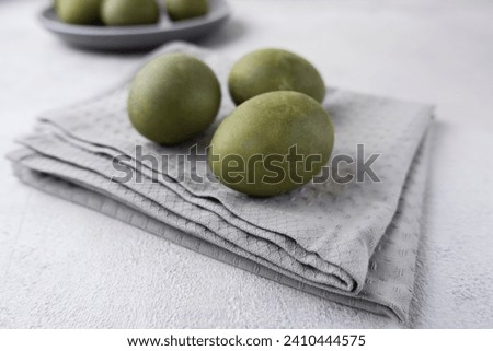 Green eggs on a gray towel on a light background. Minimal concept. View from above. Easter eggs. Photos of preparations for Easter.