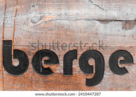 A wooden inscription mountains in German in black