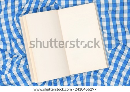Open book pages mockup on plaid cloth, top view