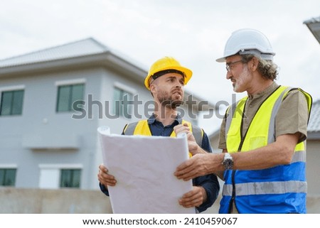 Engineers or construction contractors discussing together at the empty land about construction plan. Man talking to real estate contractor on building blueprint. Royalty-Free Stock Photo #2410459067