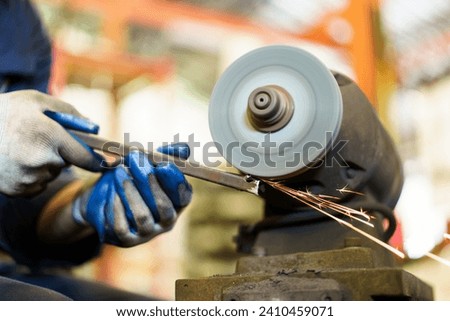 Professional metal work worker sharpening and grinding metal pipe. Man grinds metal profile in factory. Royalty-Free Stock Photo #2410459071