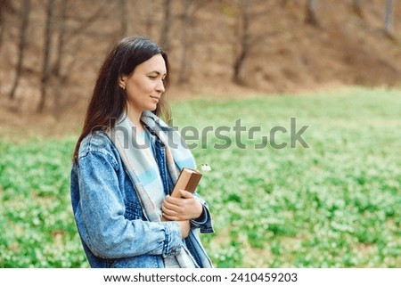 Woman enjoying spring day at nature. Lifestyle, people and spring time. Young woman with book on the walk. Time for reading. Reading book concept.