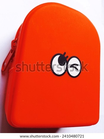An orange plastic box with a cartoon face on it.