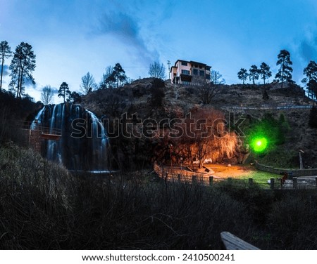 Panoramic view of waterfall and garden lit at dusk, in Guachochi, Chihuahua