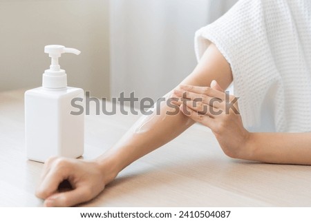 Health care, beauty smile pretty asian young woman in bathrobe, towel after shower bath at home, hand applying, putting moisturizer on her arm. Skin body cream moisturizing lotion, routine in morning. Royalty-Free Stock Photo #2410504087