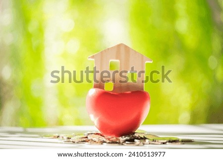 Wooden house model put in the red pot heart put on the wood on sunlight in the public park, The buying a new real estate as a gift to family or the one loved concept.